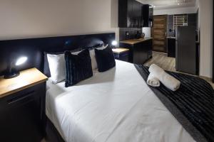 a bedroom with a large white bed and a kitchen at Fox Inn Guesthouse Lephalale in Lephalale