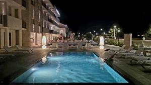a swimming pool with lounge chairs and a building at night at Hotel Perla del Gargano in San Giovanni Rotondo
