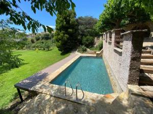 a swimming pool in a yard with a stone wall at Masía de piedra con piscina in Riudecols