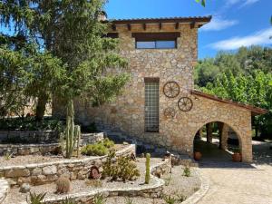 a stone house with a courtyard with cacti in front of it at Masía de piedra con piscina in Riudecols