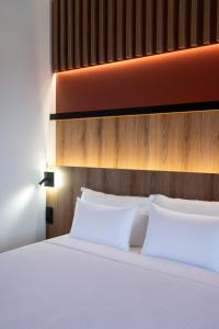 a bed with white pillows in a bedroom at ZOI Girni - Seaside Hotel in Olympic Beach