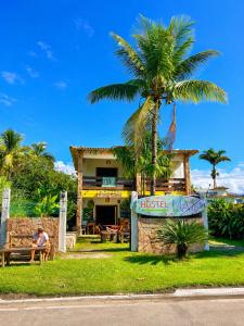 a man sitting on a bench in front of a house at Hostel Mawe in Paraty