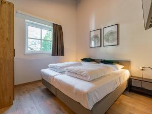a bedroom with a bed with white sheets and a window at FIIF Pinzgau in Wald im Pinzgau