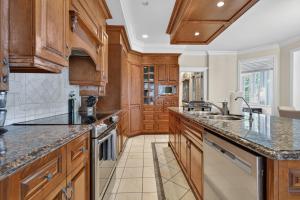 a kitchen with wooden cabinets and granite counter tops at Private Waterfront Villa 9 BR Peaceful in Laval