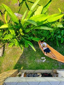a man laying on a surfboard under a tree at Hostel Mawe in Paraty