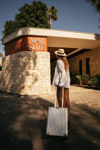 a woman with a suitcase in front of a may at Mavi Suite Turkbuku in Golturkbuku
