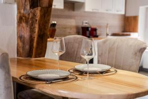 a table with two wine glasses and plates on it at Le Gîte de Jade in Dannemarie