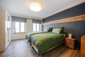 a bedroom with two beds and a blue wall at Le Gîte de Jade in Dannemarie