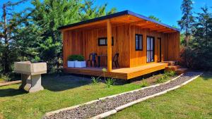 a small wooden cabin with a deck in a yard at Cabañas Pulmahue in Colón