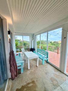 a room with two benches and a table and windows at Acacias PDD in Punta Del Diablo