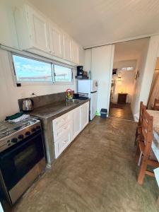 a kitchen with white cabinets and a stove top oven at Acacias PDD in Punta Del Diablo +8 photos