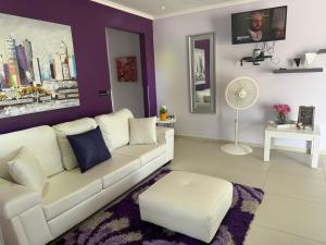 a living room with a white couch and a purple wall at Malika Apartments in Westpunt