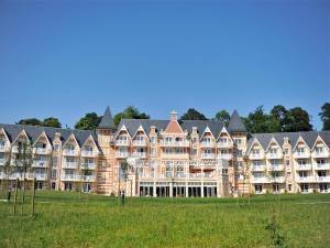 a large building with a grass field in front of it at Tranquil Apartment with Pool Access in Bagnoles de l'Orne