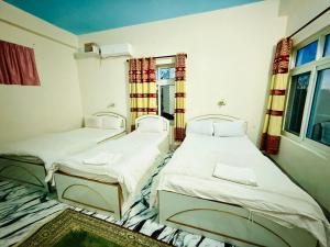 two twin beds in a room with a window at Hotel Mantra and Adventure in Sauraha +112 photos