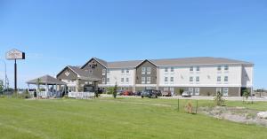 a large building with a grass field in front of it at Sierra Inn Minot in Minot