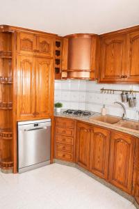 a kitchen with wooden cabinets and a sink and a dishwasher at Excelente villa With pool ibiza in Santa Gertrudis de Fruitera