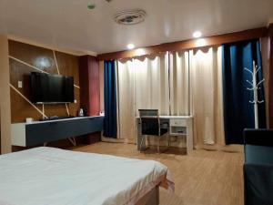 a hotel room with a bed and a desk and a television at Zhongkebole Suites in Baguio