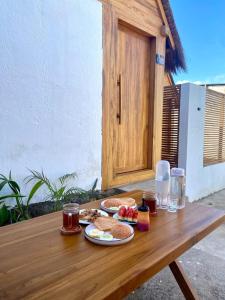 a wooden table with two plates of food on it at Aresona Cliff House in Bira