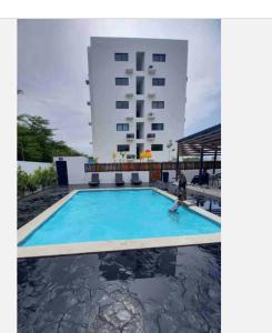 a person swimming in a pool in front of a building at Torre con ascensor y vigilancia in Santiago de los Caballeros +16 photos