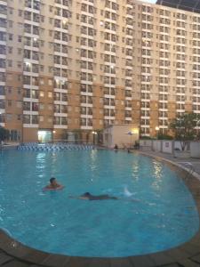 a person swimming in a large swimming pool with tall buildings at DSV Margonda Residen 2 Apartment in Depok