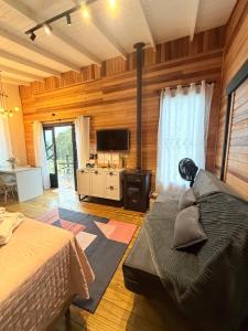 a room with a bed and a tv and a couch at Cabana do Lago com passeios a cavalo gratuito in Urubici