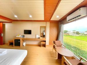 a bedroom with a bed and a desk and a window at Rồng Vàng Resort in Tri Tôn