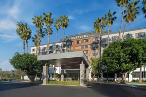 a rendering of a courtyard hotel with palm trees at Courtyard by Marriott Cypress Anaheim / Orange County in Cypress