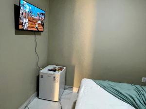 a room with a small refrigerator and a tv on the wall at Recanto Sole Luz in Piranhas