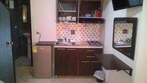 a small kitchen with brown cabinets and a sink at Apartaestudios El Cable in Manizales