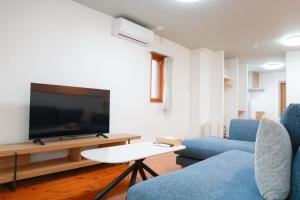 a living room with two blue chairs and a flat screen tv at Danran HAKATA in Fukuoka