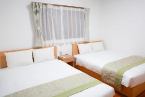a hotel room with two beds and a window at Danran HAKATA in Fukuoka
