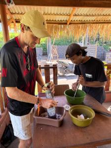 two men standing at a wooden table preparing food at Tetebatu flower in Tetebatu