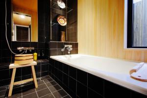 a bathroom with a white tub and black tiles at Machiya Momiji in Kyoto