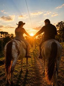 a man and a woman riding on horses at sunset at Cabana do Lago com passeios a cavalo gratuito in Urubici