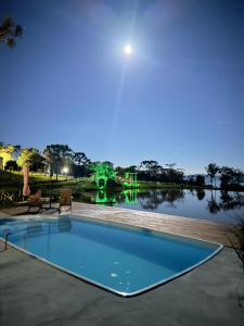 a swimming pool in front of a lake at night at CABANA AURORA com passeios a cavalo gratuito in Urubici