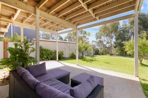 a patio with purple furniture under a wooden pergola at Leura on Ophir in Ventnor