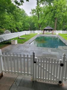 a white fence surrounds a pool with a gazebo at walnutwood in Owings Mills