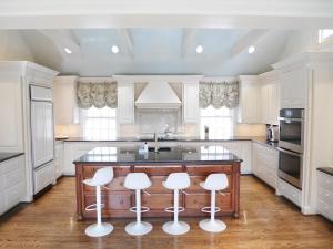 a kitchen with white cabinets and a island with bar stools at walnutwood in Owings Mills