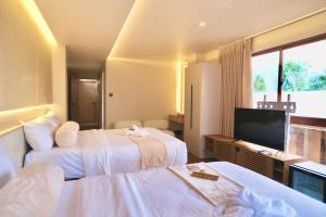 a hotel room with two beds and a flat screen tv at KHAMI HOUSE Resort in Panglao Island +32 photos