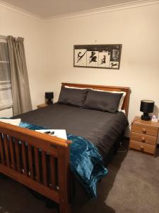 a bedroom with a wooden bed and a night stand at Larsen Apartment in Palmerston North