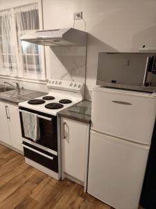 a kitchen with a white stove and a refrigerator at Larsen Apartment in Palmerston North