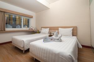 two beds in a room with a window at Whiz Hotel Falatehan Jakarta in Jakarta +26 photos