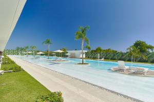 a large swimming pool with chairs and palm trees at Cana Rock in Punta Cana