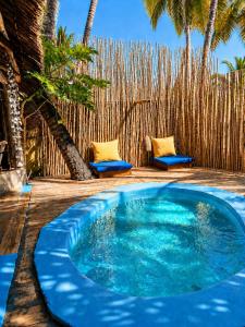 a blue pool with two chairs and a fence at Karibuni Marafiki in Bwejuu