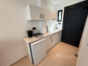 a small kitchen with white cabinets and a black door at Captains Studios & Apartments in Kavos