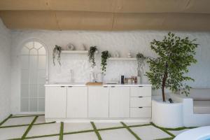 a kitchen with white cabinets and a tree in it at Makyra by Bohemian Jogja Villas in Kejayan
