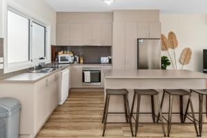 a kitchen with white cabinets and a large island with bar stools at San Remo Bay Views Phillip Island Gateway in San Remo +31 photos
