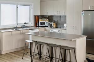 a kitchen with white cabinets and a counter with stools at San Remo Bay Views Phillip Island Gateway in San Remo