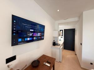 a living room with a large flat screen tv on the wall at Captains Studios & Apartments in Kavos