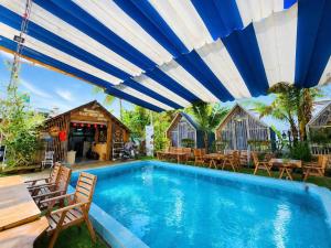 a swimming pool with chairs and a blue and white umbrella at Dak Nguyen Homestay DakLak in Buon Ma Thuot